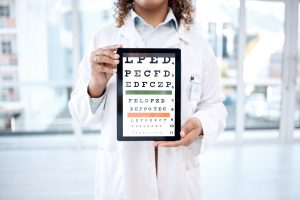 Hands, optometry chart and tablet screen in hospital for vision examination in clinic. Healthcare.