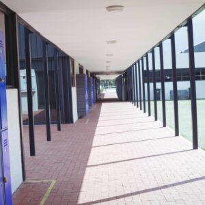 An empty hallway in a school setting, with lockers on the left.