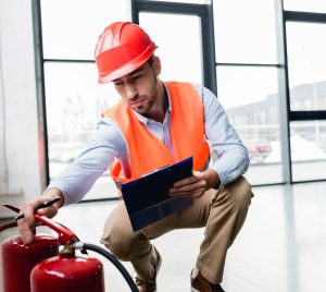 A fire risk assessor inspecting a fire extinguisher